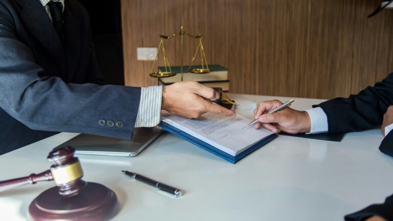 Attorney reviewing a settlement document at a desk with scales of justice