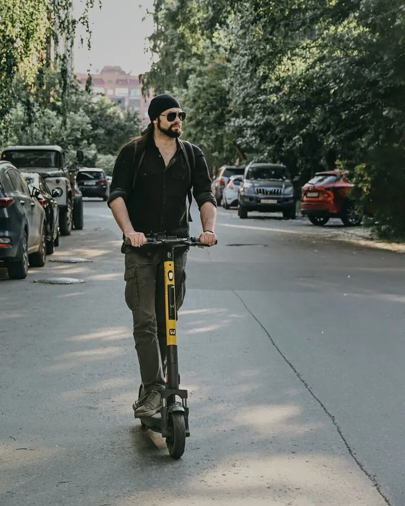 A man riding an electric scooter down a city street