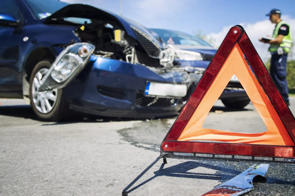 Two damaged cars after a collision with a warning triangle on the road