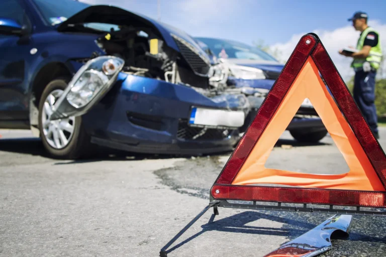 Two damaged cars after a collision with an emergency warning triangle in the road