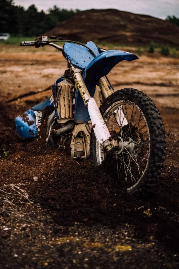 A motorcycle lying on its side in the dirt after a crash