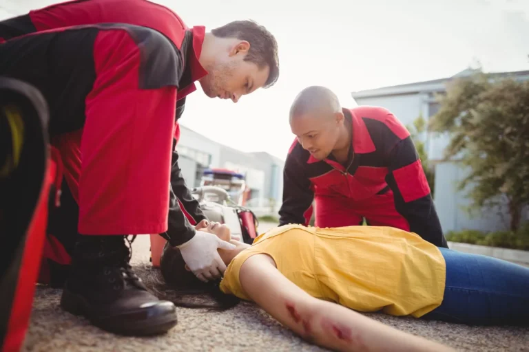 Paramedics treating an injured person at the scene of a crash